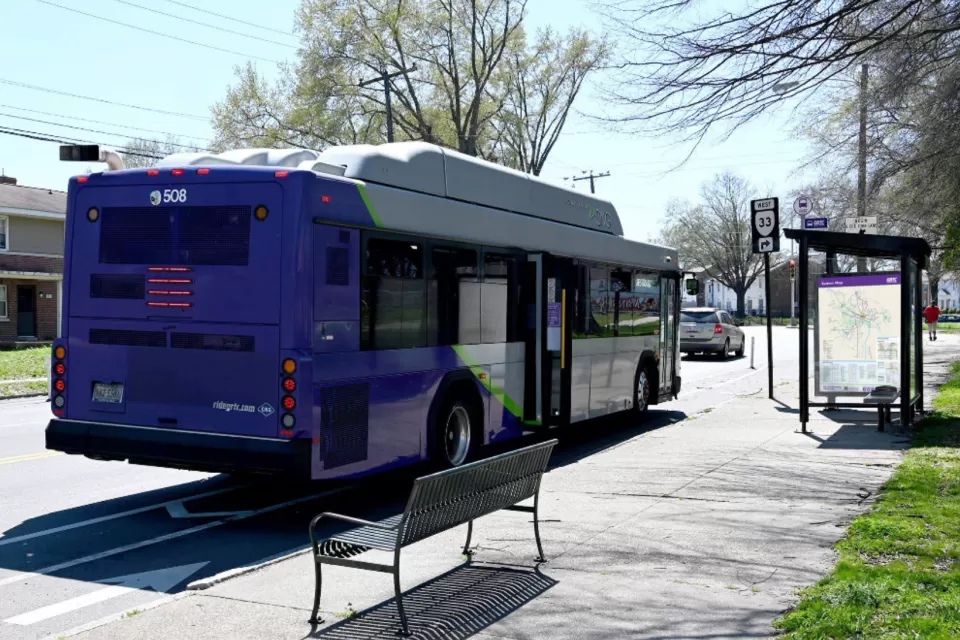 Purple GRTC bus stopped at a bus station with bench and shelter in Richmond, Virginia.